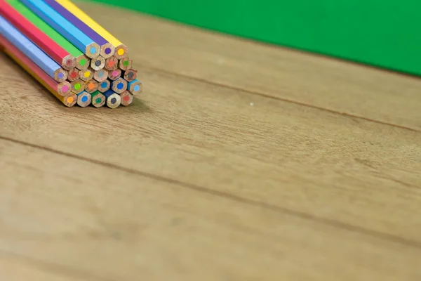 Pila de lápices de color sobre mesa de madera con fondo verde . — Foto de Stock