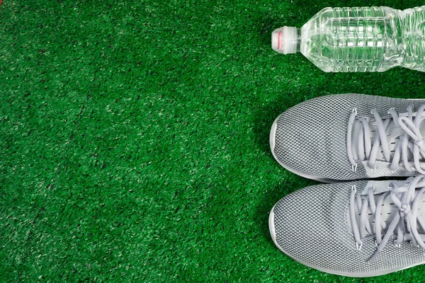 Gray Sports Running Zapatos y botella de agua sobre hierba verde . — Foto de Stock