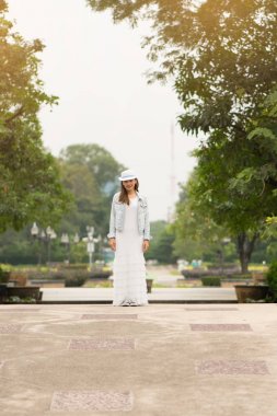 Genel Park'ta denim ceket ile beyaz maxi elbise giyen mutlu kadın. Doğa ile mutlu bir hayat kavramı.