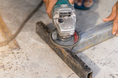 Fabrika elektrik tekerlek üzerinde çelik yapı taşlama için işçi.