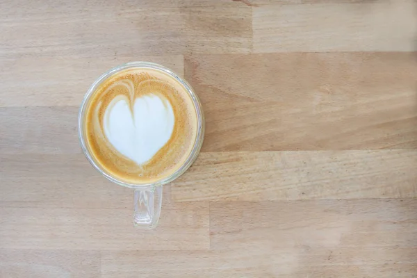 Hot coffee with milk foam on wooden table at cafe