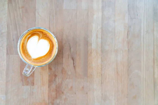 Hot coffee with milk foam on wooden table at cafe