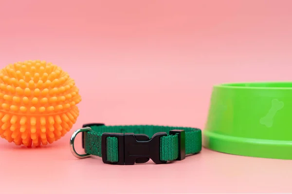 Collar para mascotas y juguete de goma con tazón sobre fondo rosa — Foto de Stock