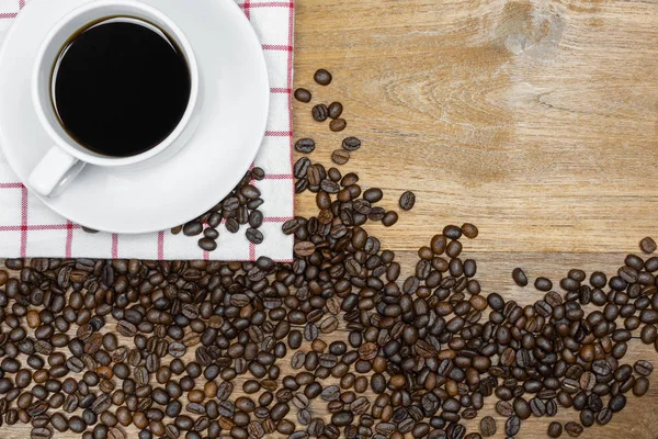 Heißer Kaffee mit Kaffeebohnen auf Holzgrund — Stockfoto