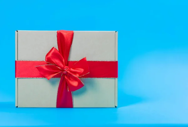 Geschenkdoos met rood lint op blauwe achtergrond — Stockfoto