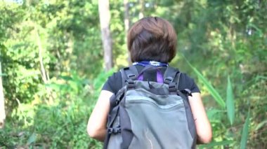 Hippi kadın dağda yürüyüş yapmak için ormana doğru yürüyor.