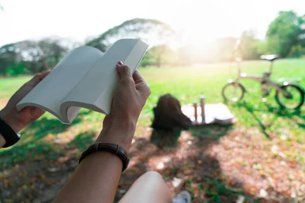 Hand holding a book at garden.  Relax outdoor concept