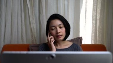 Akıllı telefon kullanan ve ofisteki bilgisayara bakan bir iş kadını. Ev konseptinde çalış