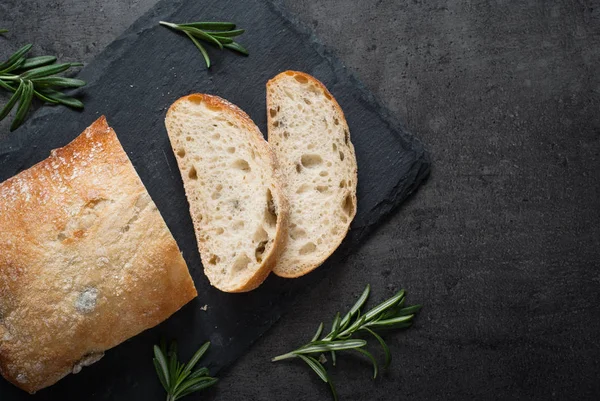 Italská ciabatta chléb na černé břidlice s bylinkami a olivami. — Stock fotografie
