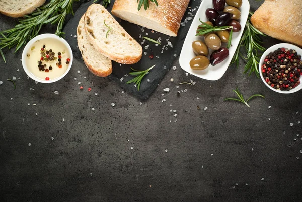 Włoska ciabatta pieczywo na czarny Łupek z ziołami i oliwki. — Zdjęcie stockowe