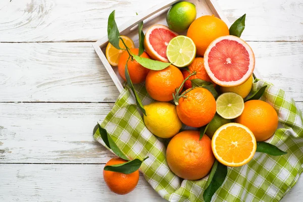 Citrusové plody v Dřevěný tác na stůl bílý. — Stock fotografie