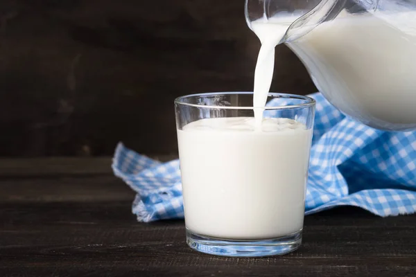 Verter leche de una jarra en un vaso . — Foto de Stock