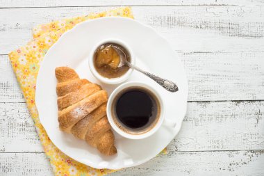 Kruvasan reçel kahve turuncu jice beyaz tahta masada. 