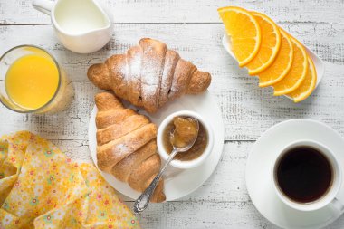 Kruvasan reçel kahve turuncu jice beyaz tahta masada. 