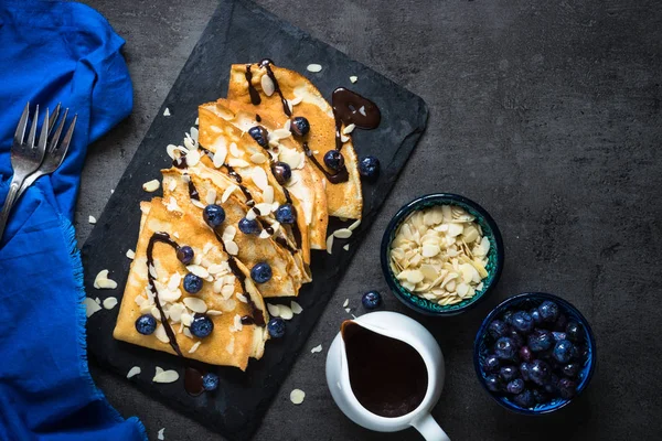 Crepes ai mirtilli scaglie di mandorle e salsa al cioccolato su bla — Foto Stock