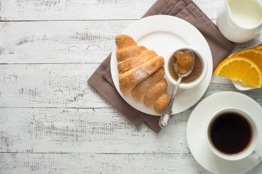 Kruvasan reçel kahve beyaz tahta masada.