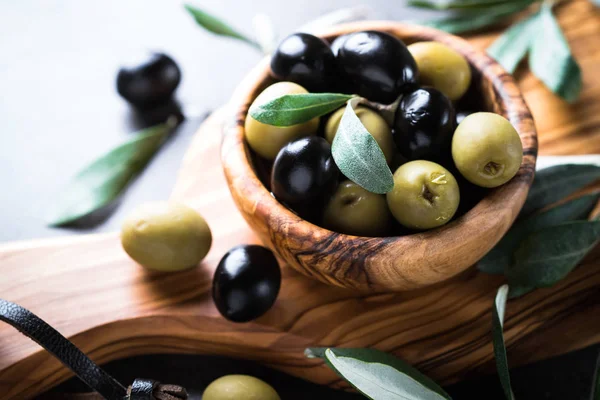 Black and green olives in wooden bowl