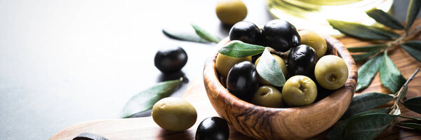Black and green olives in wooden bowl