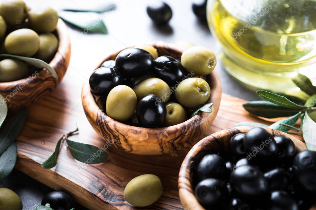 Black and green olives in wooden bowl