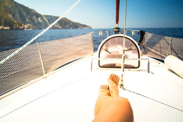 The legs of a woman on the background of a yacht and the sea.
