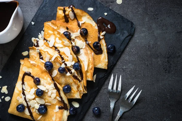 Crepes ai mirtilli scaglie di mandorle e salsa al cioccolato su bla — Foto Stock