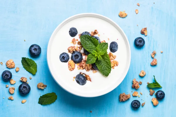Греческий йогурт мюсли и черника на голубом столе . — стоковое фото