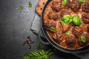 Siyah bir zemin üzerine domates soslu köfte. 