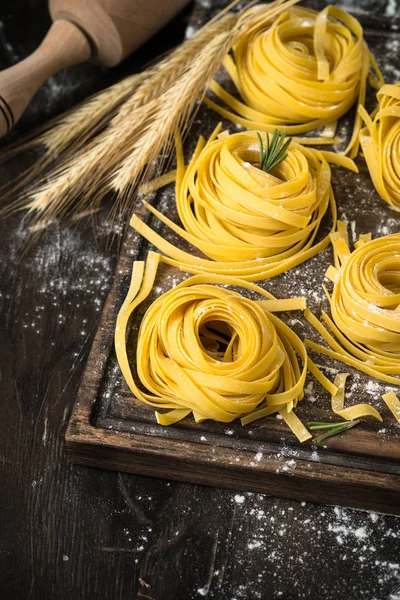 Fresh homemade pasta tagliatelle at wooden table.