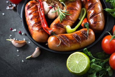 Fried Barbekü sosis taş masada sebzeli.