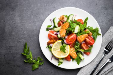 Taze salata somon ve sebzeler siyah arka plan üzerine.
