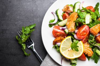 Taze salata somon ve sebzeler siyah arka plan üzerine.