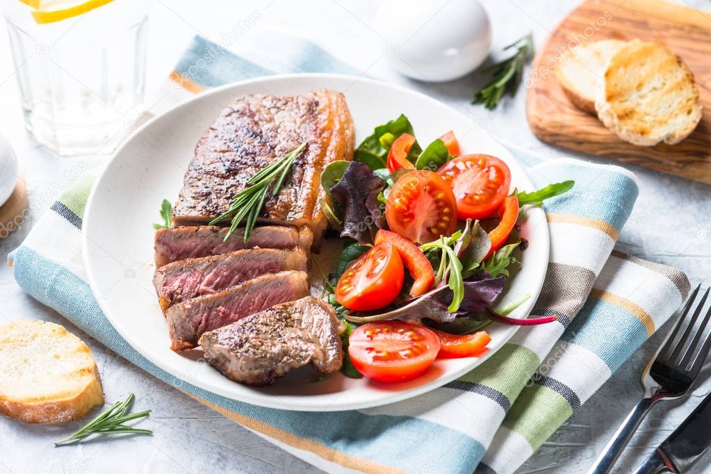 Grilled beef striploin steak with fresh salad.