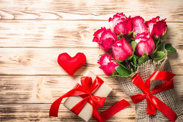 Rosa roja y caja de regalo en mesa de madera . — Foto de Stock