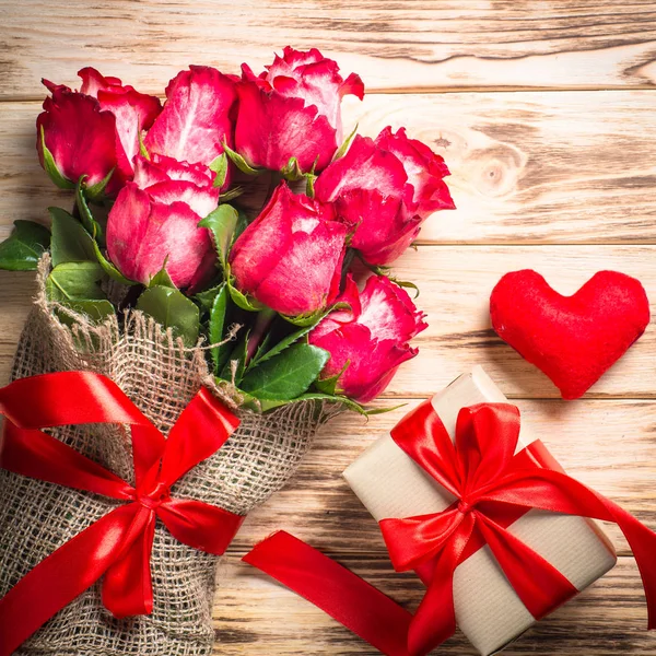 木桌上的红玫瑰花和礼物盒. — 图库照片