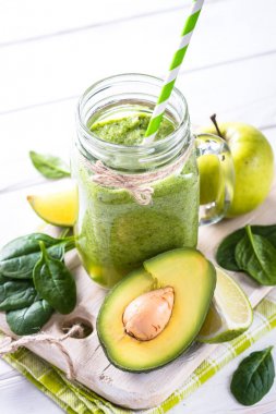 Yeşil smoothie ve malzemelerin üzerine beyaz ahşap masa.