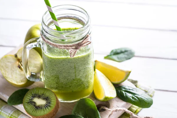 Frullato verde e ingredienti su tavolo di legno bianco . — Foto Stock