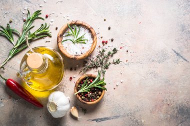 Spices and herbs background - olive oil rosemary on stone table. clipart