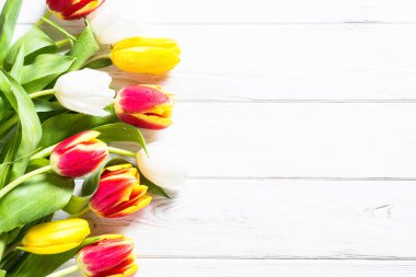 Beyaz ahşap masa üzerinde kırmızı sarı ve Beyaz Lale.