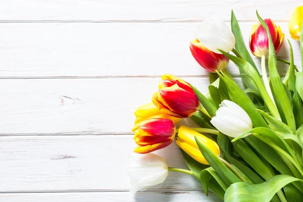 Tulipanes rojos amarillos y blancos sobre mesa de madera blanca . —  Fotos de Stock