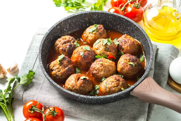 Meat balls in tomato sauce in a frying pan.
