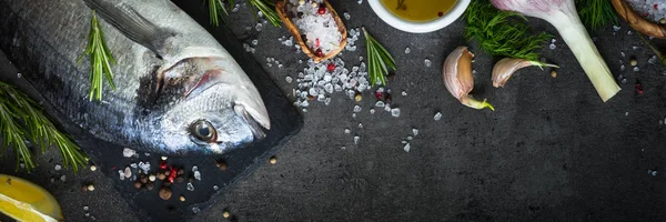 Dorado and ingredients for cooking at black. — Stock Photo, Image