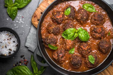 Siyah bir zemin üzerine domates soslu köfte. 