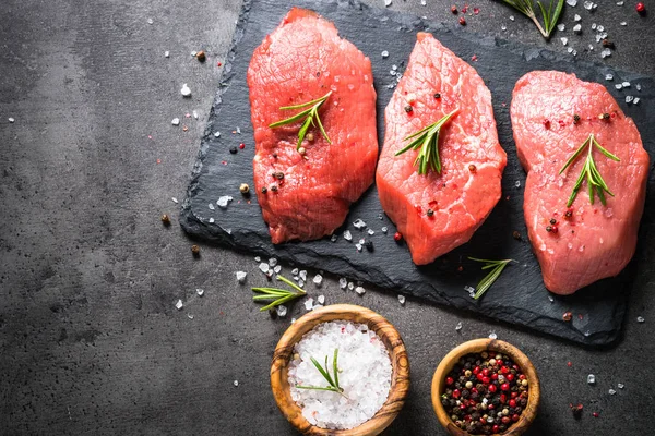 Hovězí steak s rozmarýnem a koření na černém pozadí — Stock fotografie