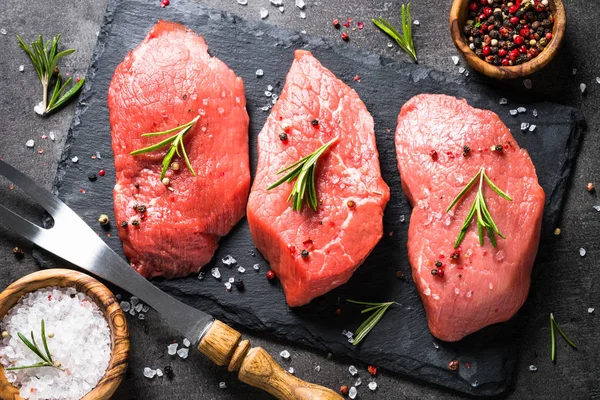 Biberiye ve baharat siyah arka plan üzerine sığır eti biftek — Stok fotoğraf