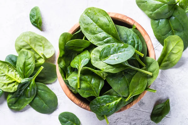 Baby spinach on gray stone table top view. — Stock Photo, Image