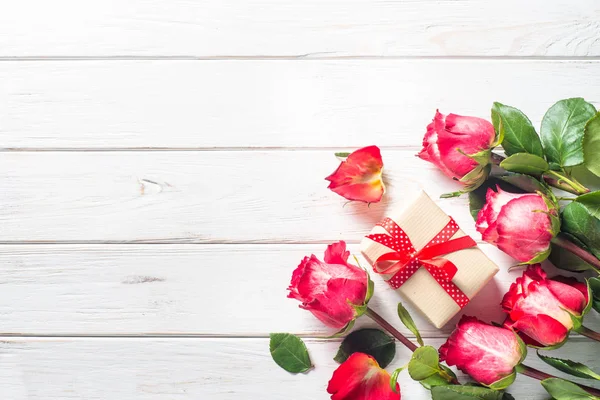 Rosa roja y caja de regalo en mesa de madera . — Foto de Stock