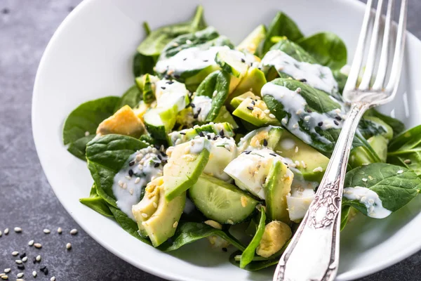 Green salad with avocado, spinach egg and cucumber.