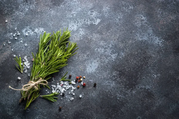 Zweige von Rosmarin, Pfeffer und Knoblauch auf dunklem Steingrund — Stockfoto