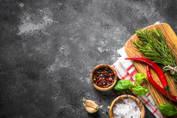 Fűszerek, fűszernövények és konyhai eszközök fekete kő asztal fölé. — Stock Fotó
