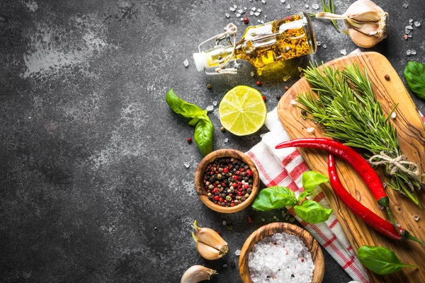 Olívaolaj, gyógynövények és fűszerek a sötét kő asztal. — Stock Fotó